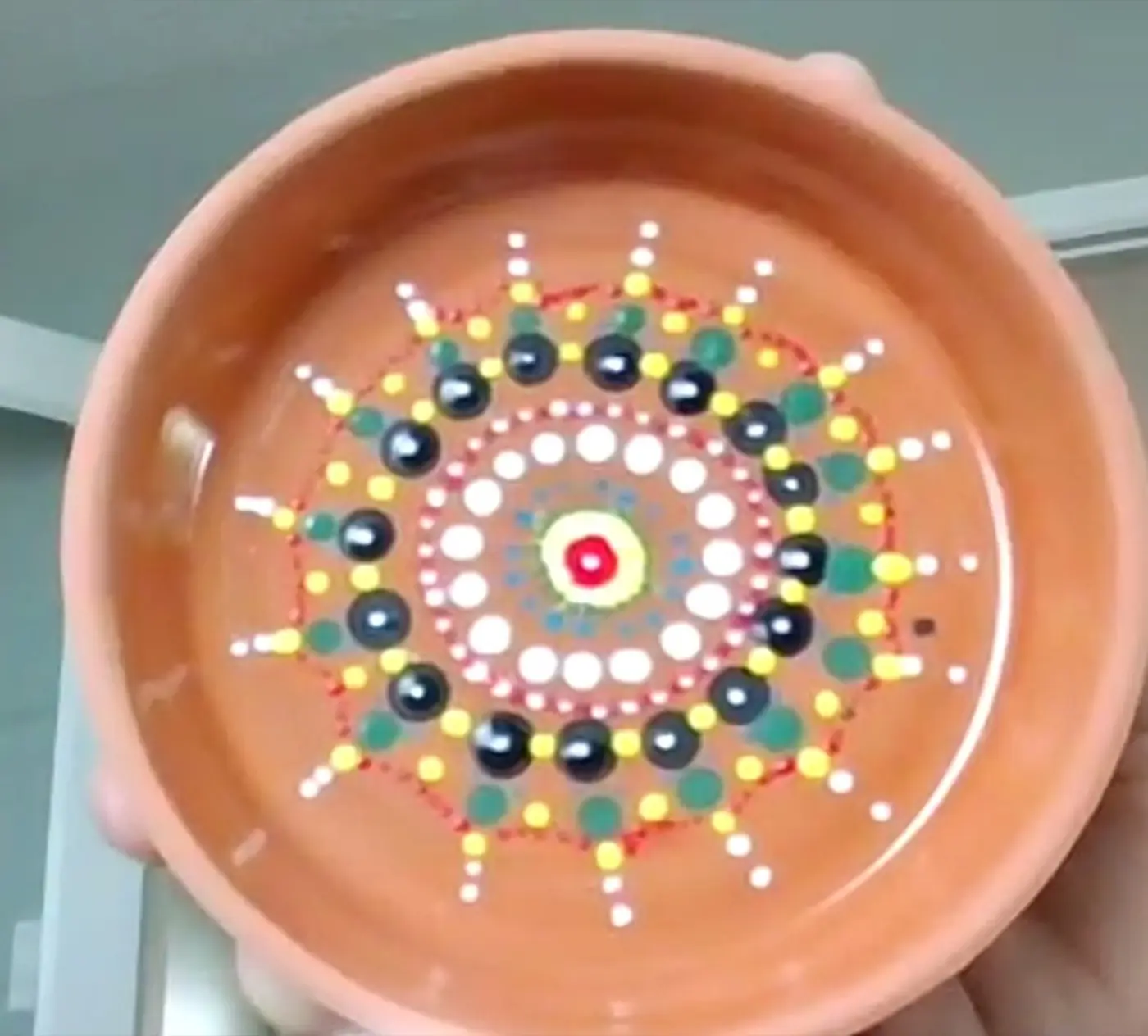 A hand-painted dot mandala on a terracotta dish