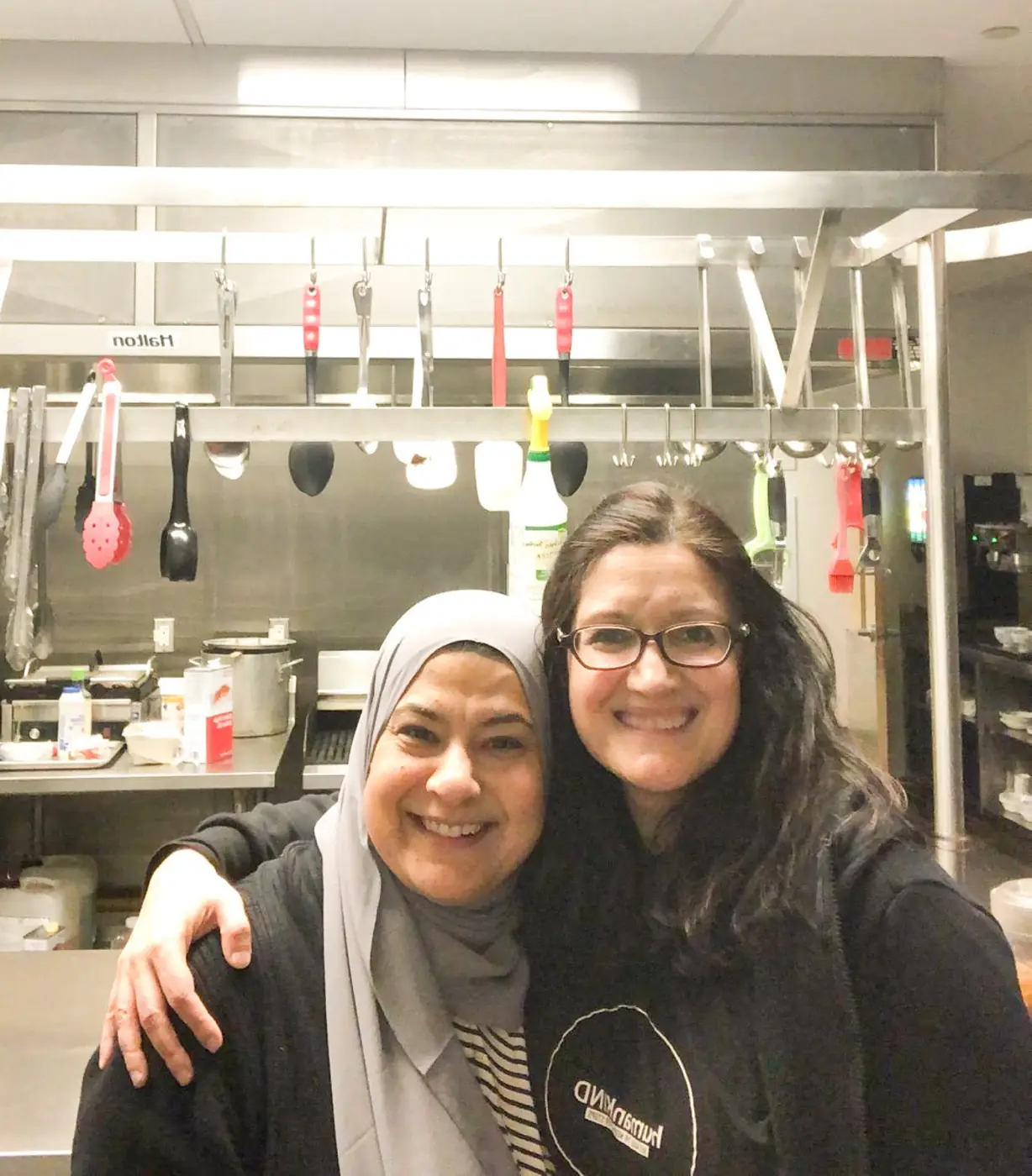 Two volunteers hugging in a kitchen