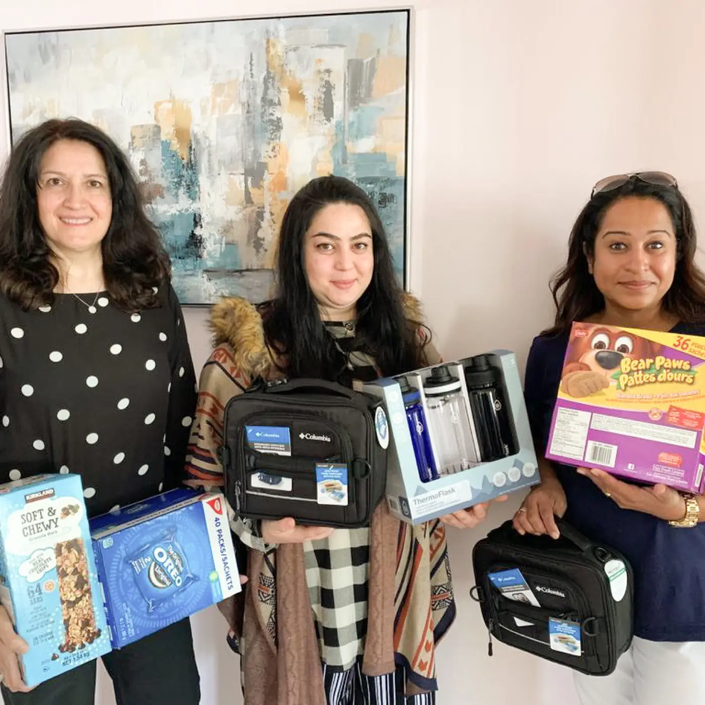 Three volunteers holding lunch bags, water bottles and snacks for Project Lunchbox