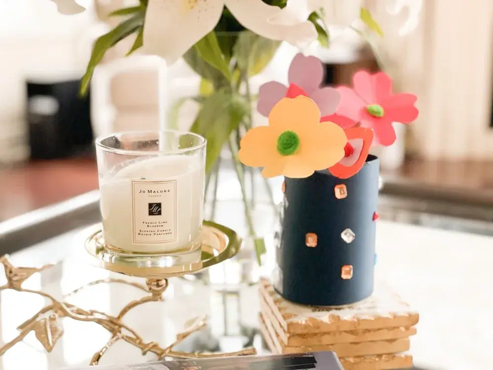 A candle beside a handmade paper flower craft