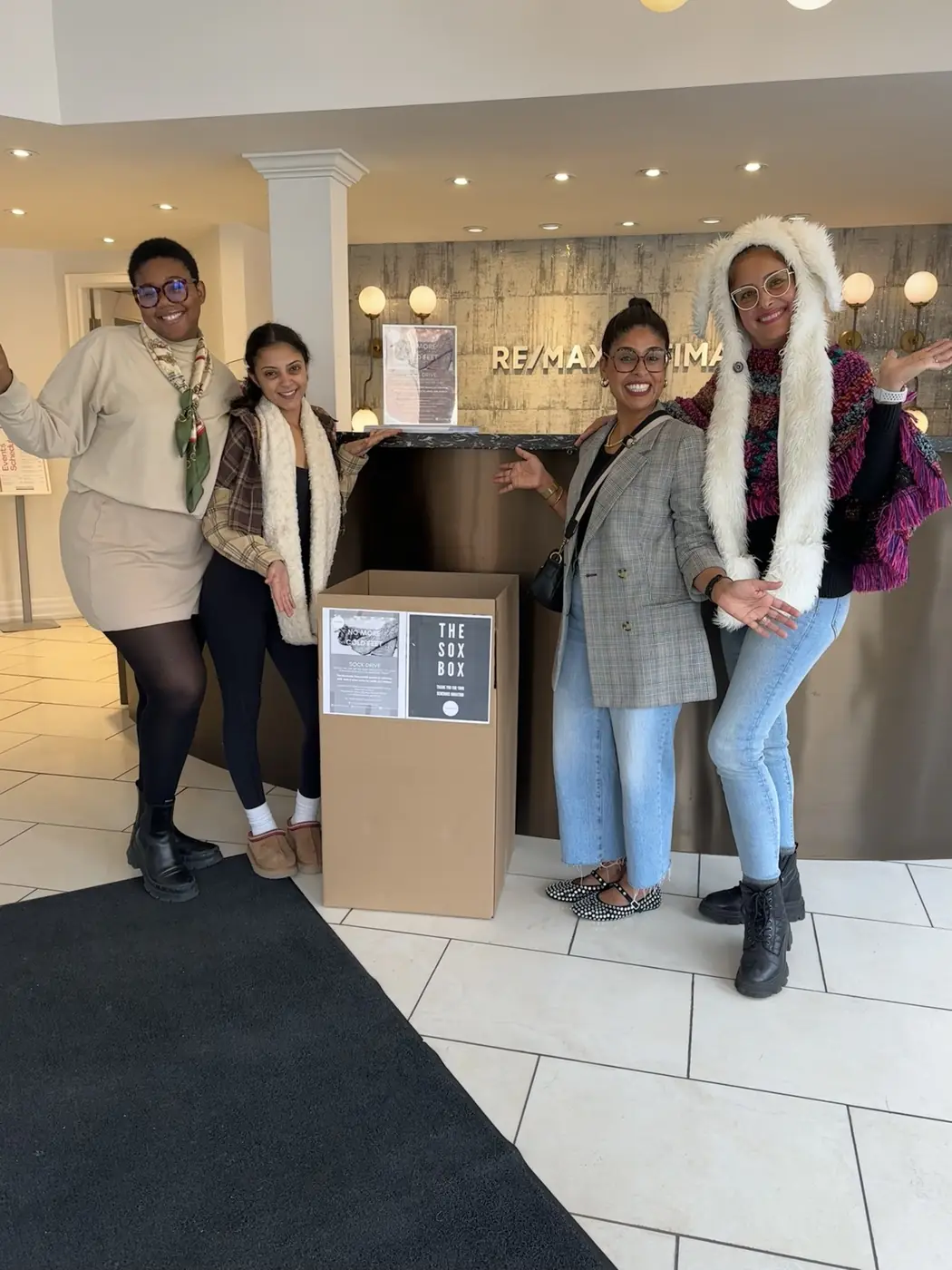 People posing beside a Sox Box collection box at a local business