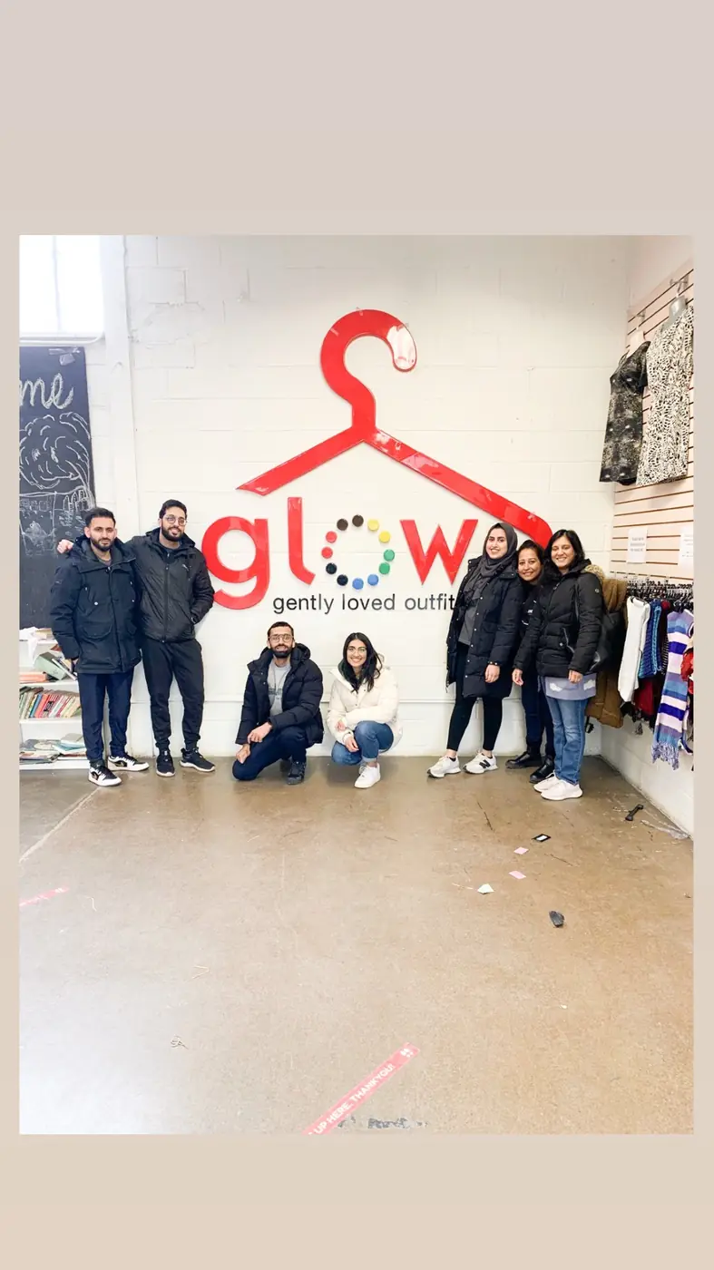 Volunteers posing in front of a colourful mural at a partner thrift shop